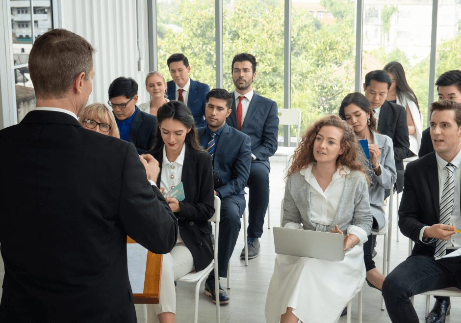 A man in suit and tie standing next to a group of people.