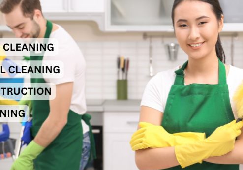 A man and woman in green aprons cleaning the kitchen.