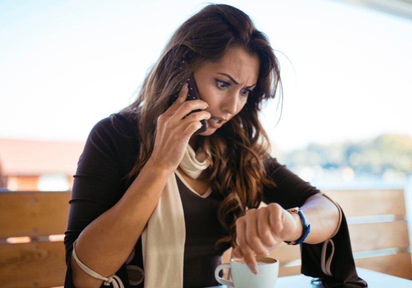 A woman on the phone looking at her watch.