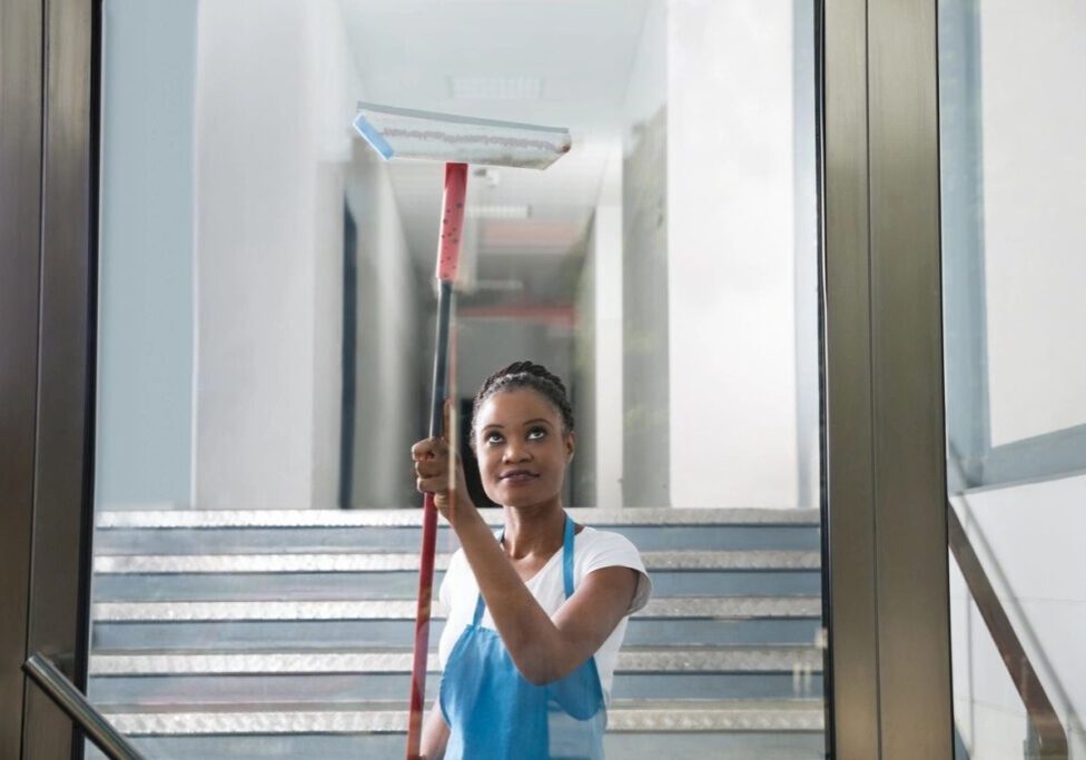 A woman holding a mop and smiling for the camera.